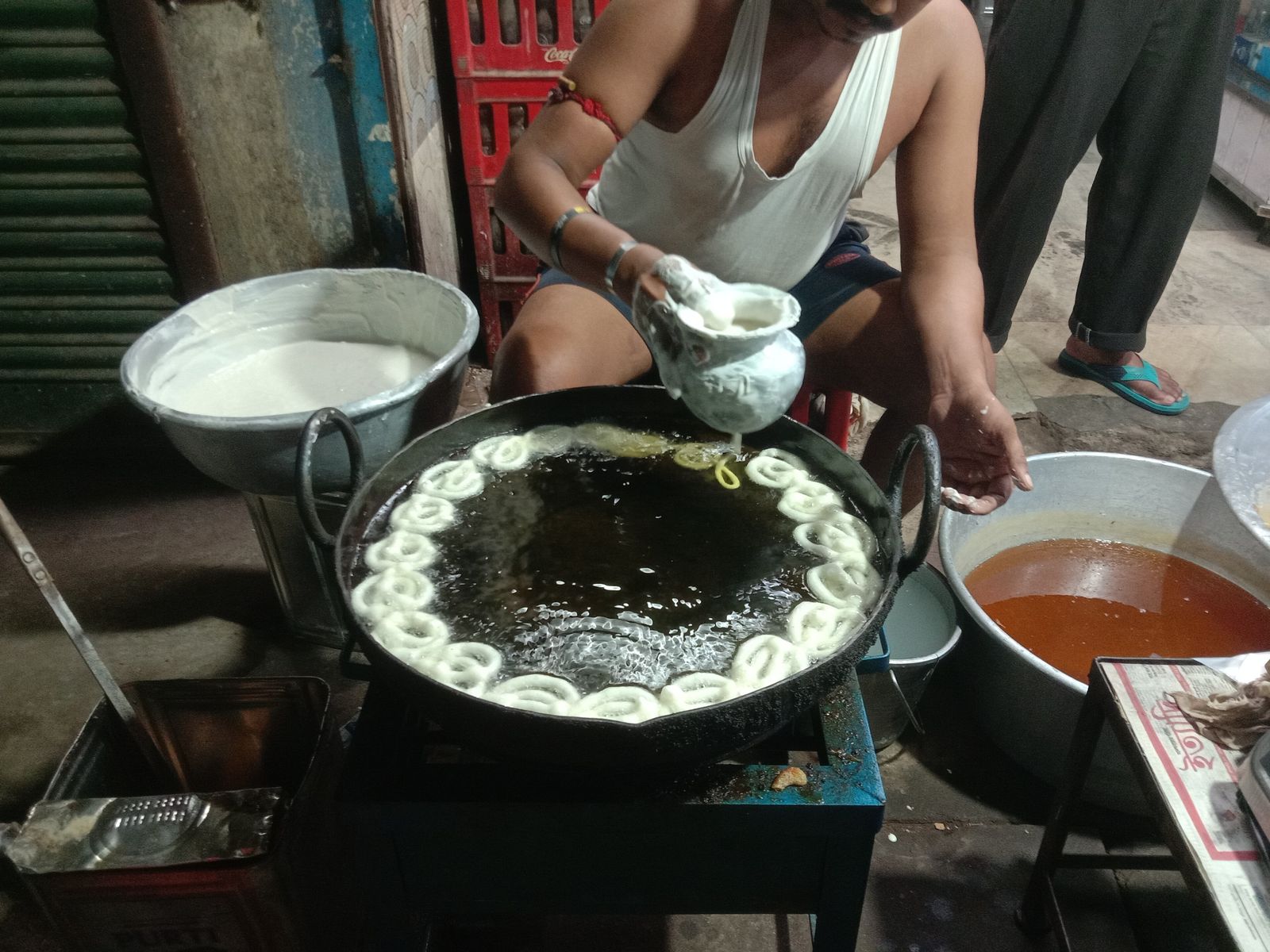 Jalebis being fried in a wide pan of oil at a local sweet shop
