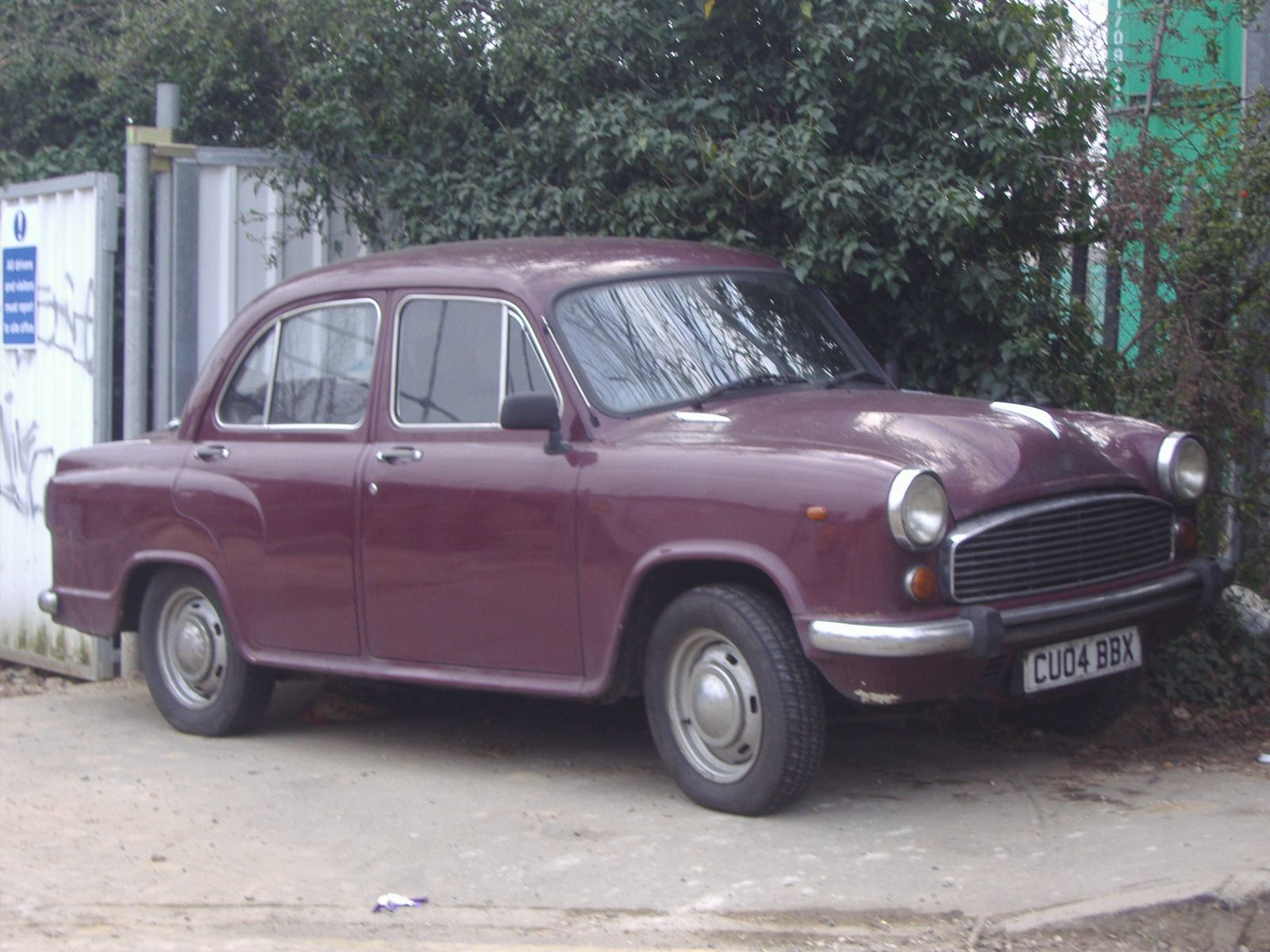 A white Hindustan Ambassador car parked on an Indian street