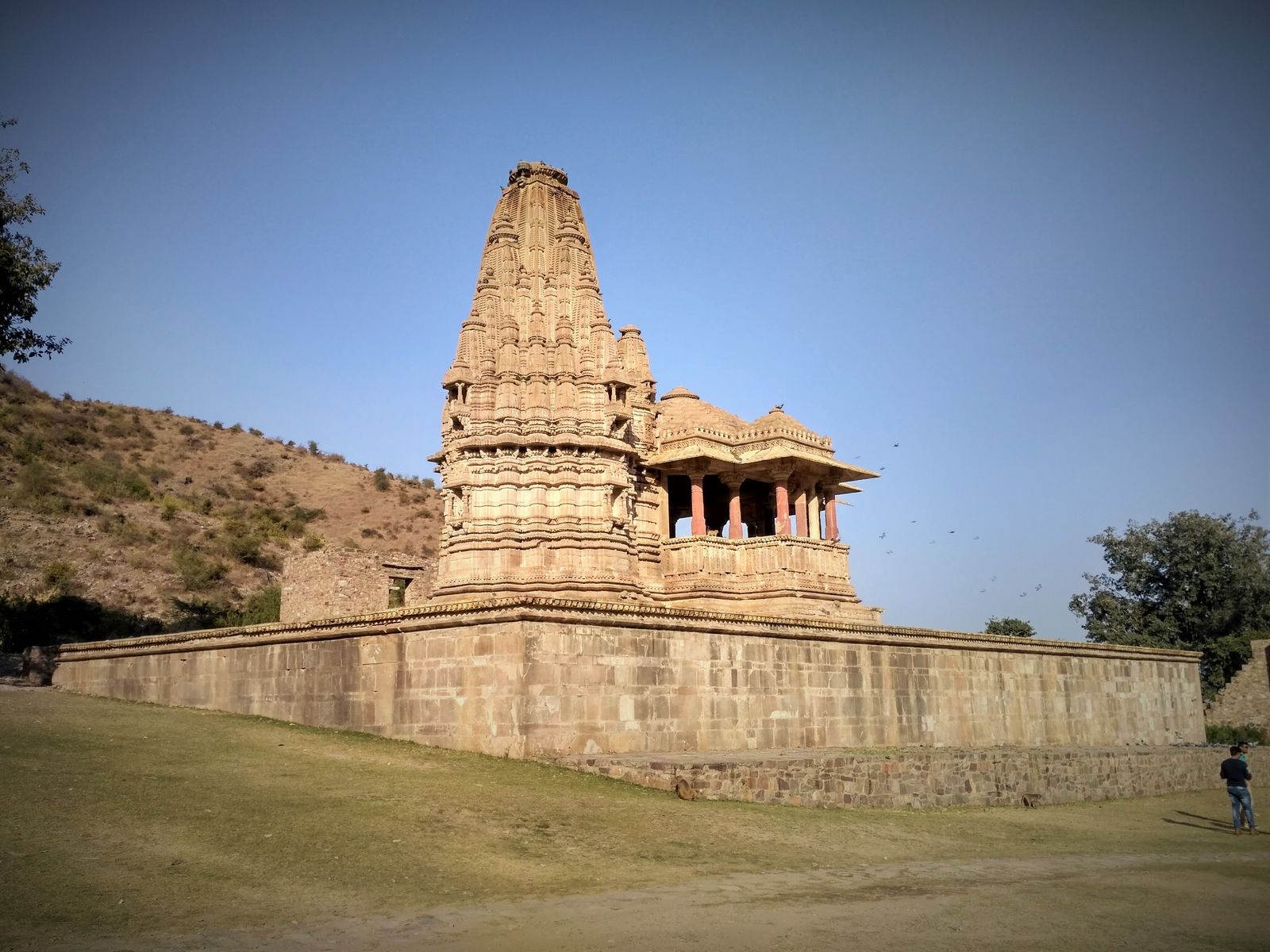 A carved stone temple on a high plinth among the ruins of Bhangarh