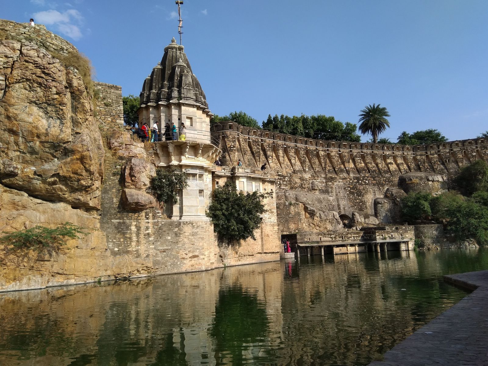 Stone steps leading down to the green water of Gaumukh Kund, a spring-fed tank on the edge of Chittorgarh Fort