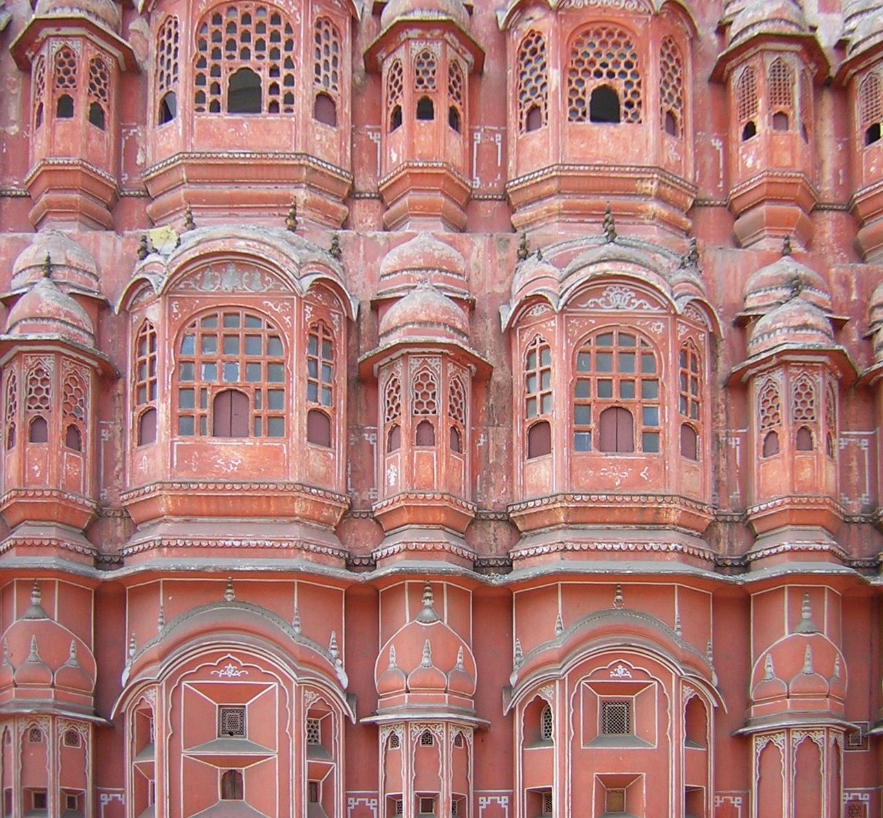 Rows of small pink sandstone jharokha windows on the facade of Hawa Mahal in Jaipur