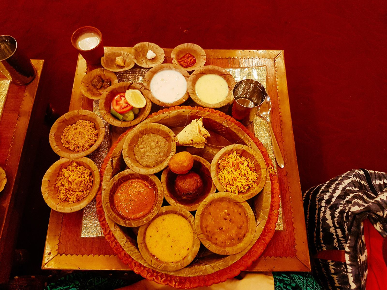A Rajasthani thali of small bowls of dal, curries, chutneys and breads around a steel plate