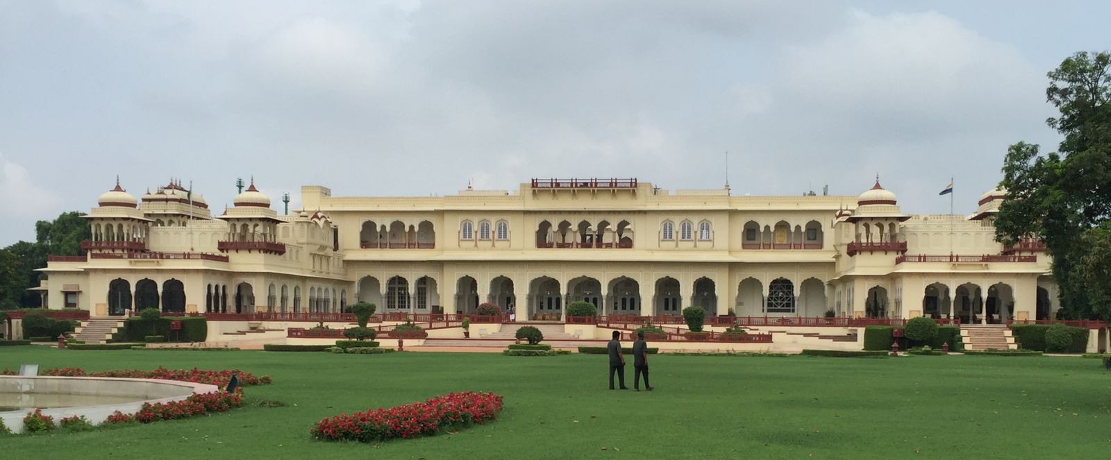 The domed and arcaded sandstone facade of Rambagh Palace in Jaipur seen from its gardens