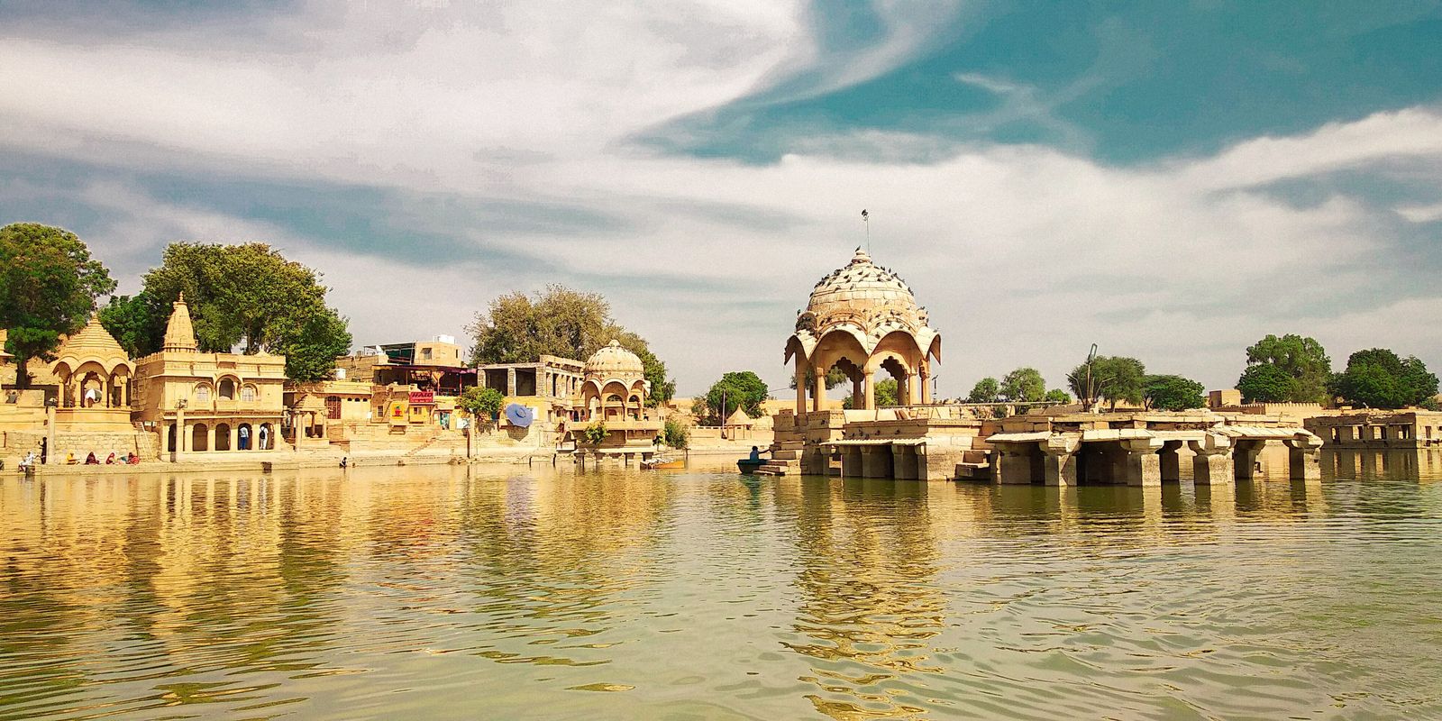 Pavilions and chhatris standing in the still water of Gadisar Lake in Jaisalmer at sunrise