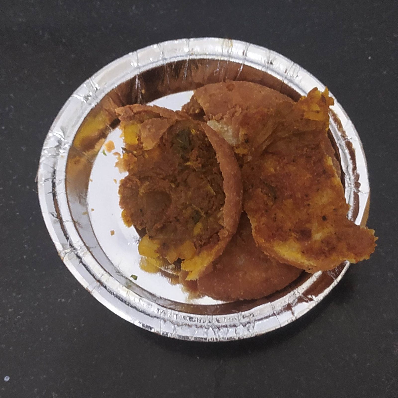 Round golden pyaaz kachoris served with tamarind and green chutney