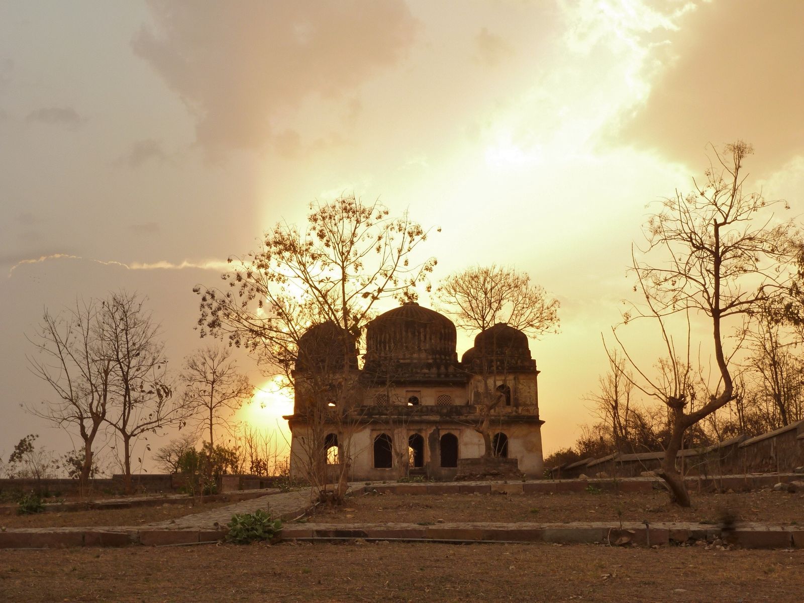 The Betwa River flowing over smooth granite rocks near Orchha with temples on the far bank