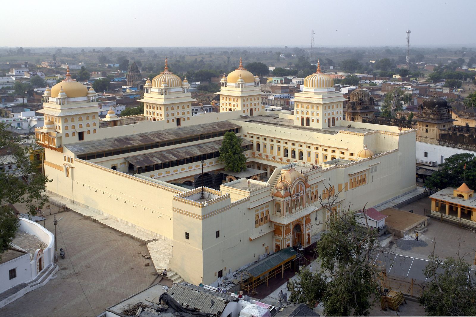 The pink and yellow facade of the Ram Raja temple in Orchha with pilgrims in the square