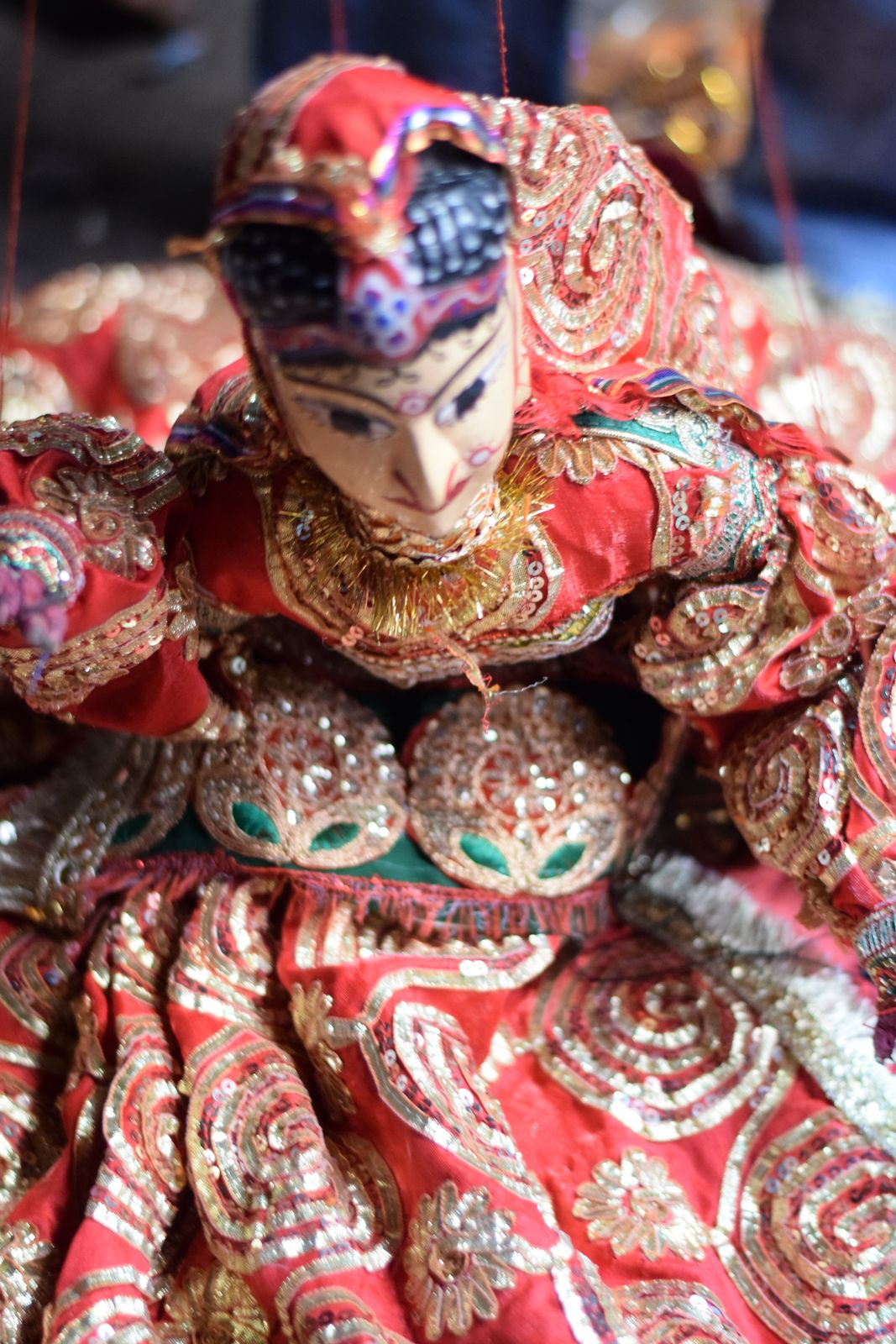 Rajasthani kathputli string puppets with painted wooden faces, bright skirts and turbans hanging in a row