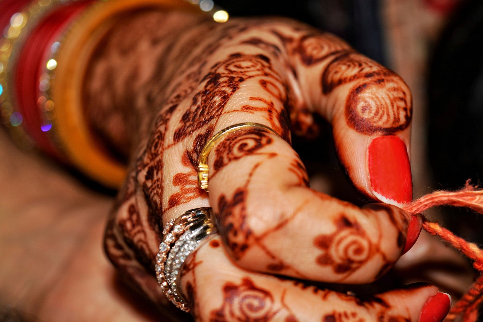 A pair of hands covered in intricate dark Rajasthani henna patterns of flowers, peacocks and fine lines