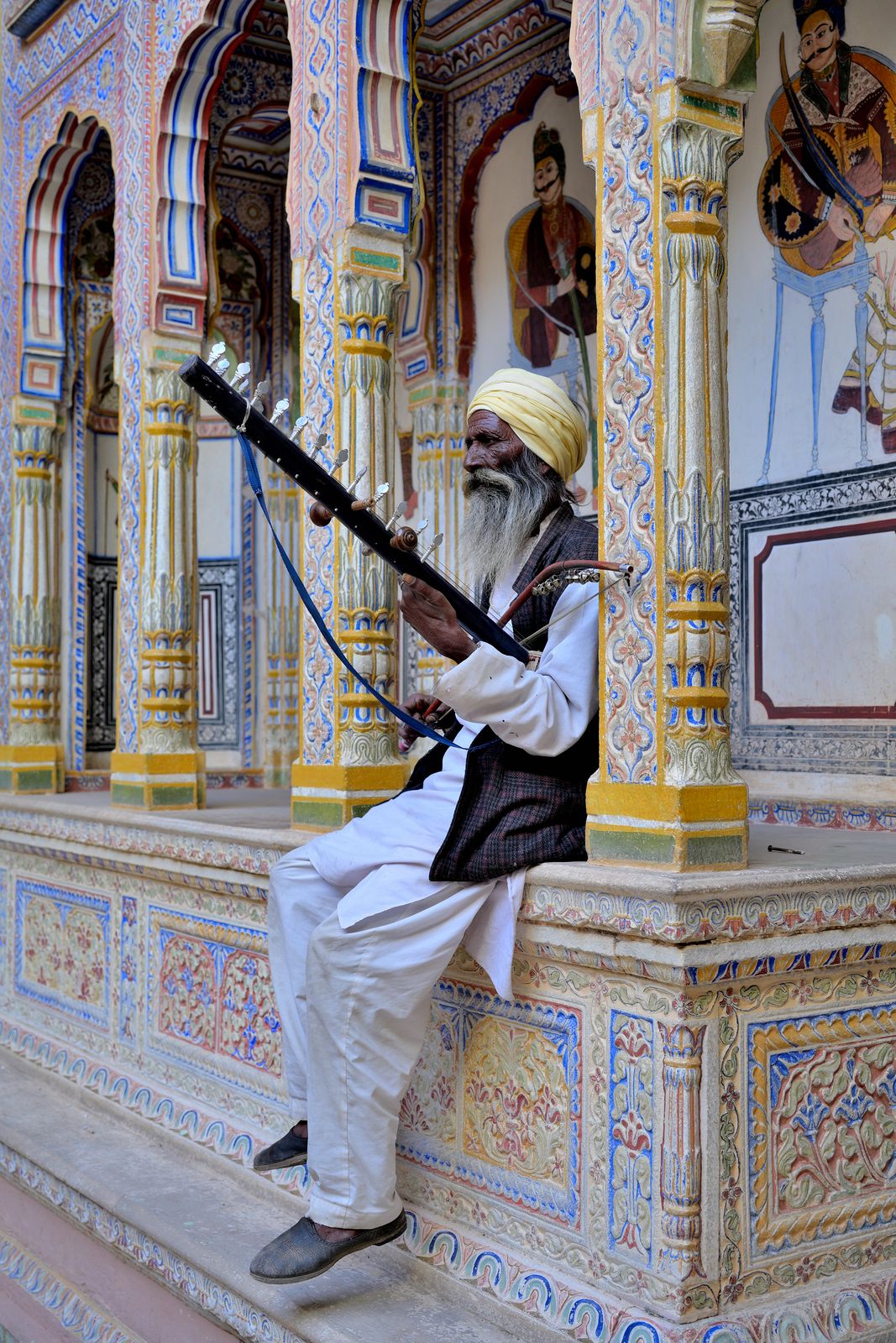 A Shekhawati musician playing beside a painted haveli wall